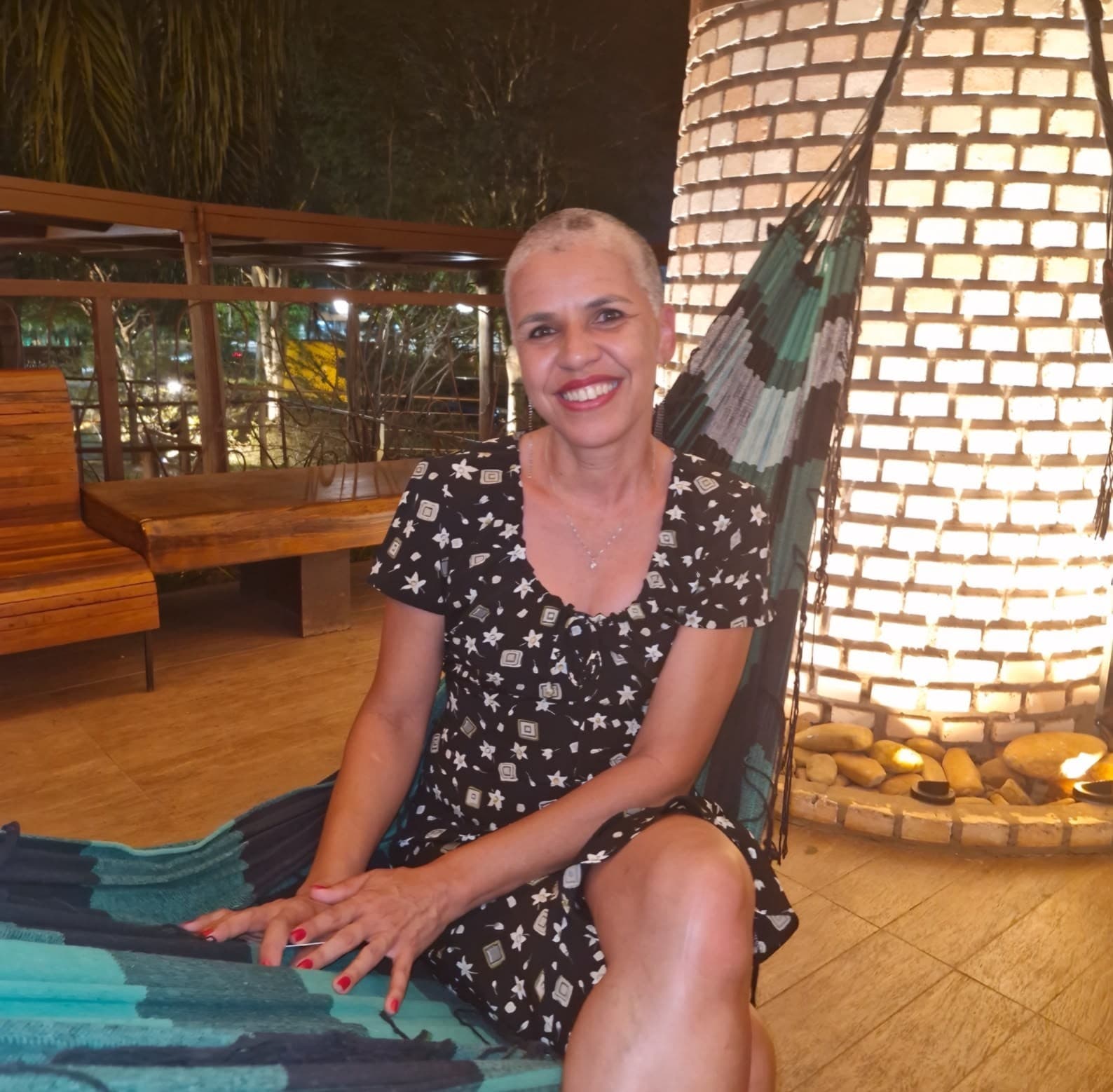 Leila Campelos sorrindo, em um ambiente acolhedor e natural